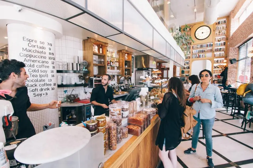 Customers ordering at the counter of a bright, busy cafe