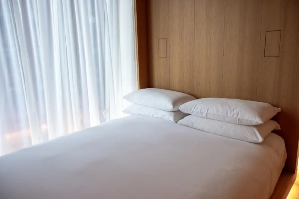 A freshly made hotel bed with crisp white pillows