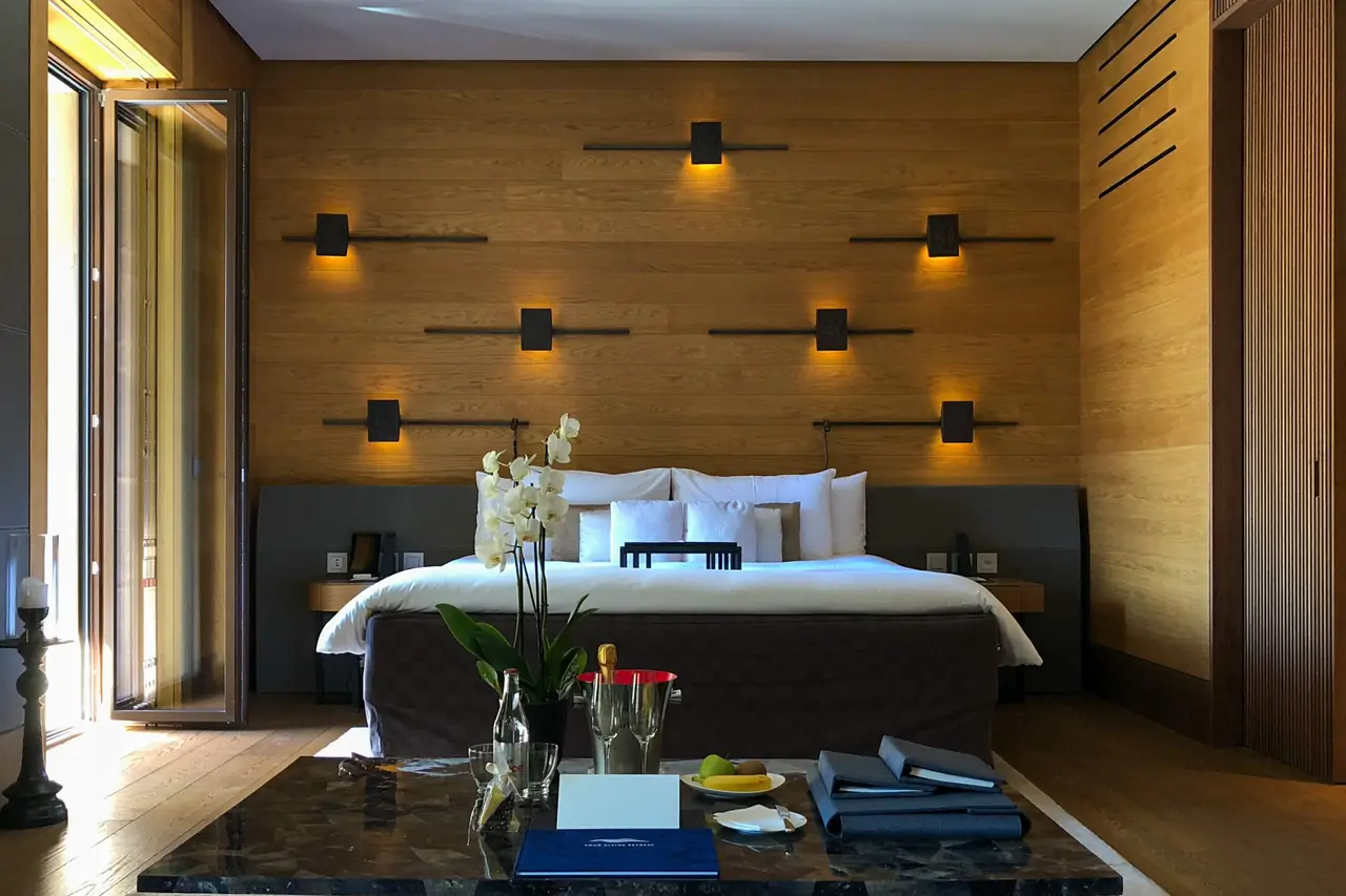 A hotel suite with a large bed, a wood-panelled wall and a coffee table