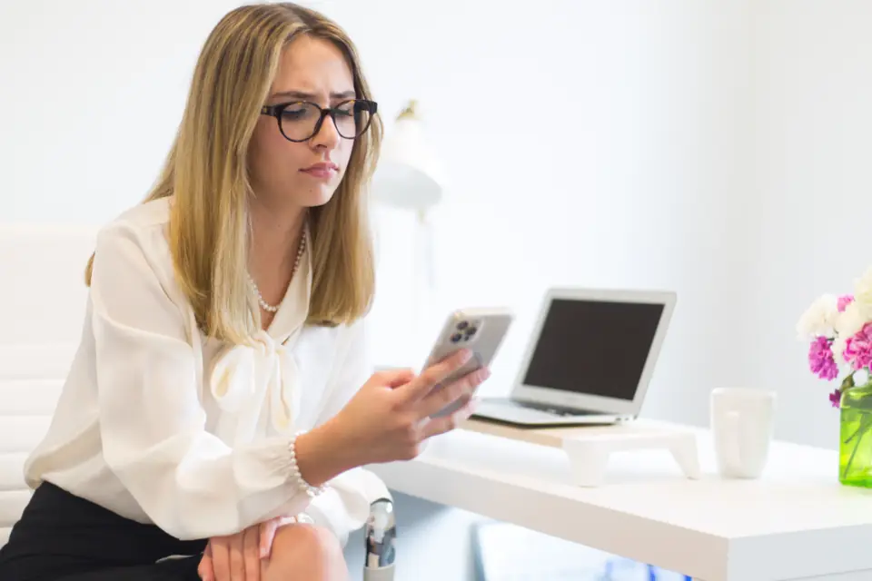 A business owner at a desk reading a customer message on their phone