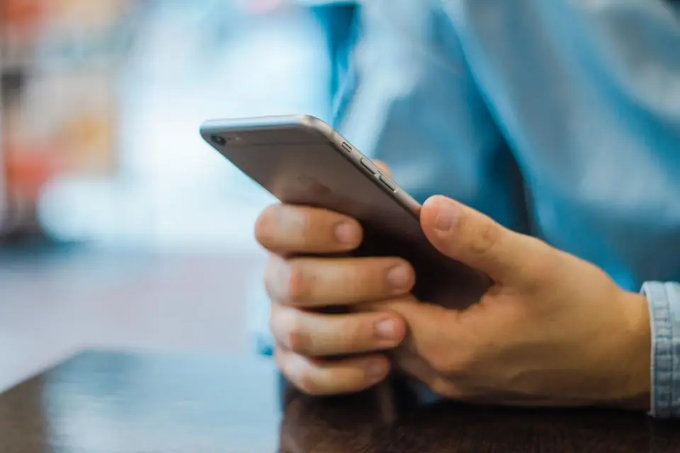A customer holding a smartphone at a table