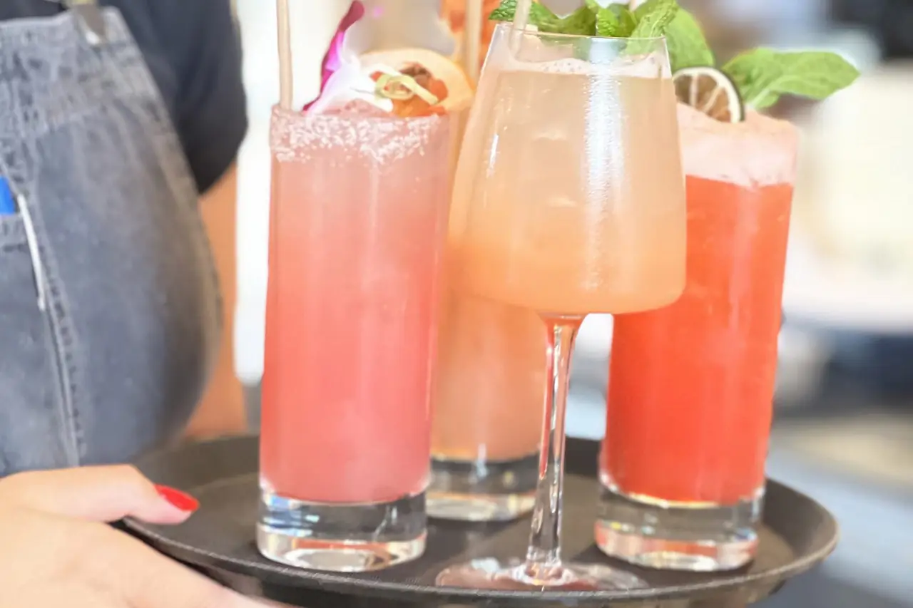 A server carrying a tray of colourful cocktails