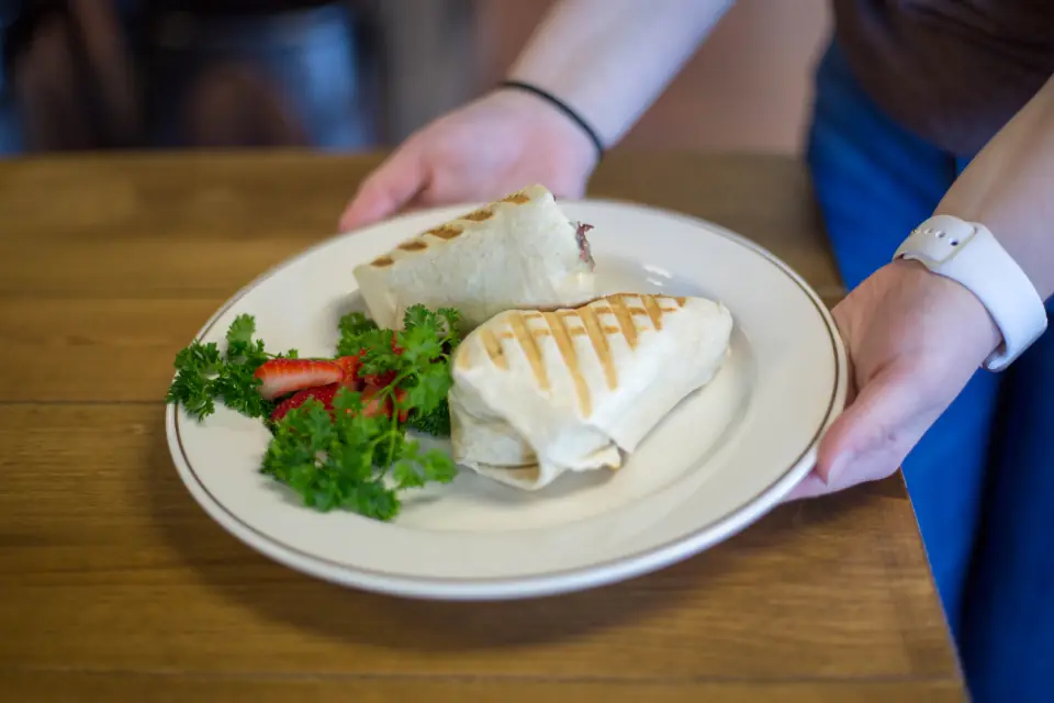 A server sets a plate of food down on a guest's table