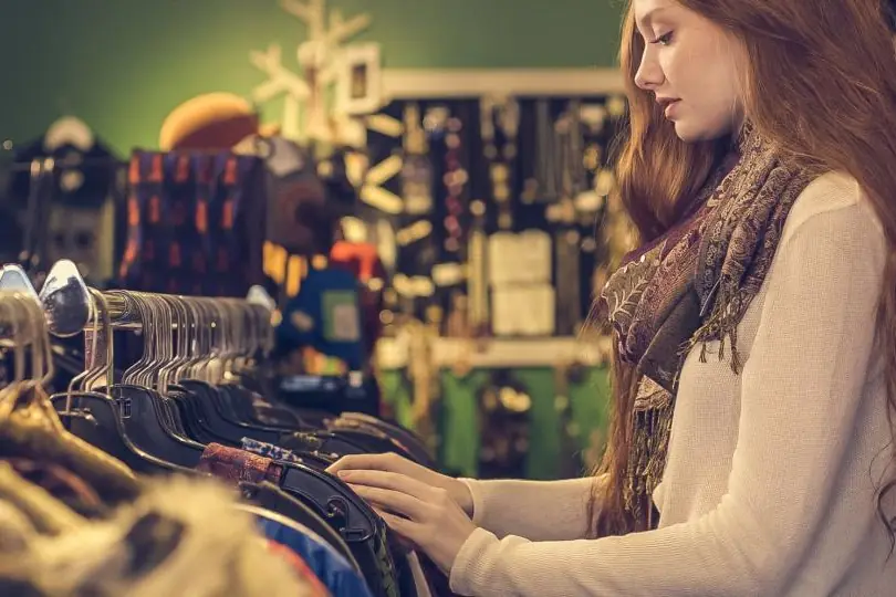 A shopper looking through clothes on a rail in a store